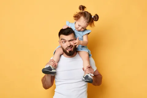 kid sitting on adult shoulders