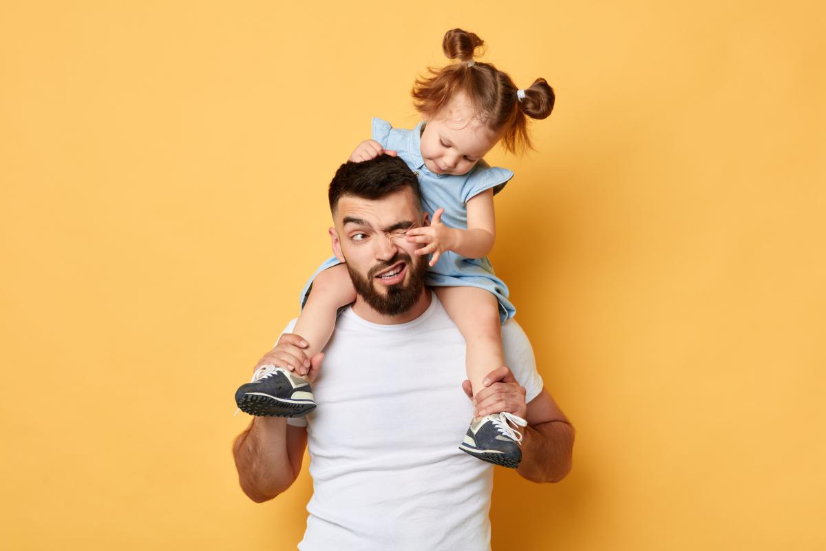 kid sitting on adult shoulders